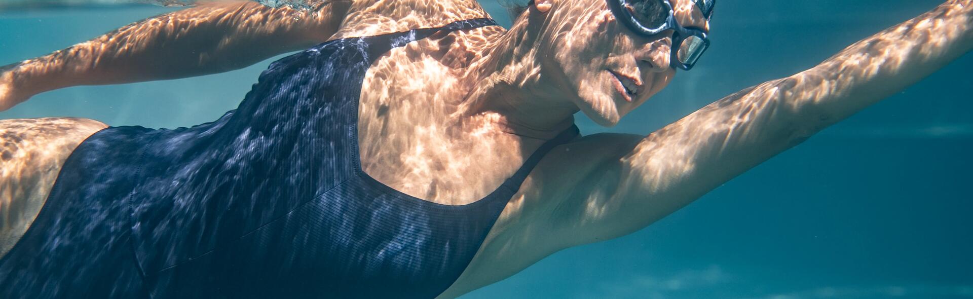 kobieta w stroju pływackim i okularkach pływackich pływająca na basenie