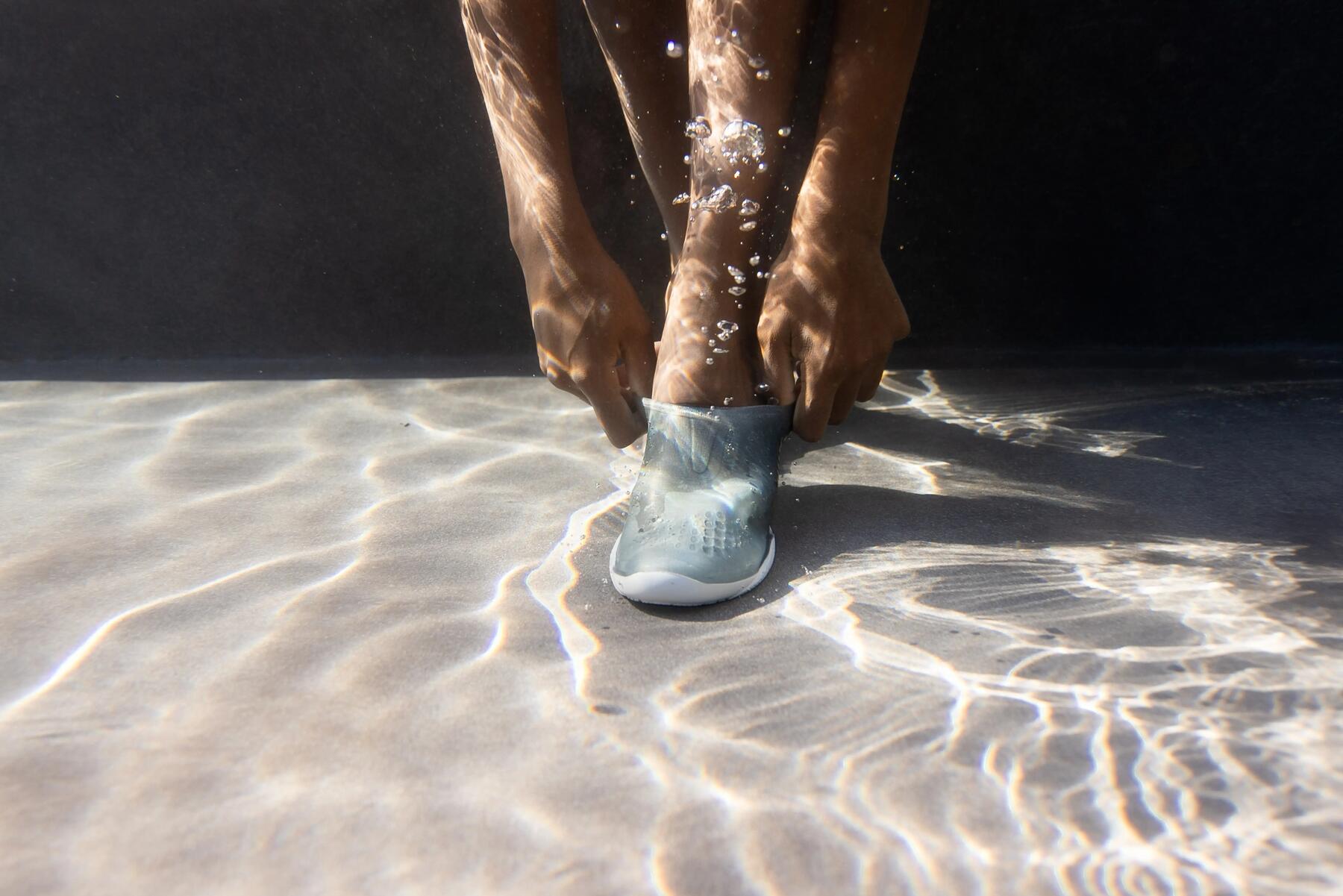 Frau richtet ihre Wasserschuhe unter Wasser