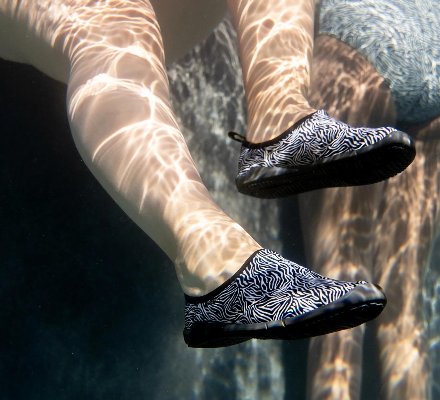 Frau sitzt am Beckenrand und trägt Schuhe für Aquagym
