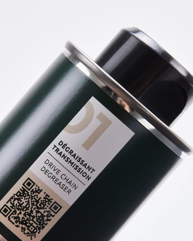 Nahaufnahme einer dunkelgrünen Sprühdose für „Drive Chain Degreaser“ (Dégraissant Transmission) mit der großen Ziffer „01“, einem QR-Code und dem deutschen Text „Kraftvolle Reinigung“ am unteren Bildrand. Die Dose ist leicht geneigt vor einem hellen Hintergrund dargestellt.
