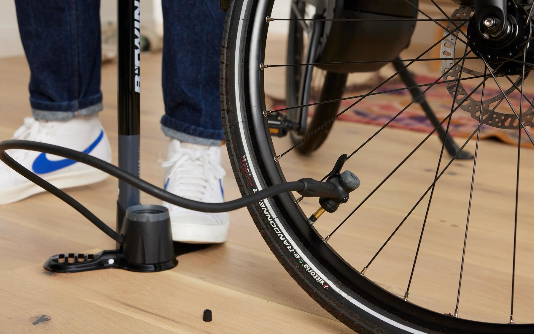 Man inflating a bike tyre at home with a floor pump