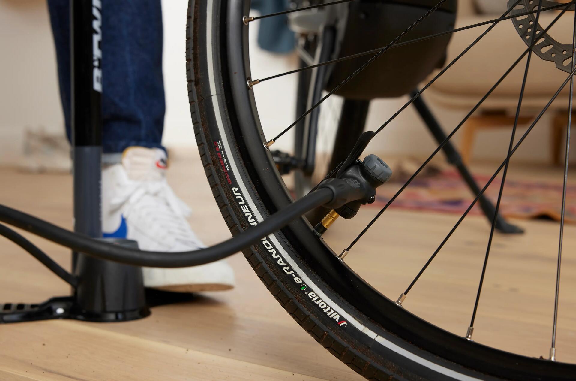 Mężczyzna pompujący koło od roweru mini pompką