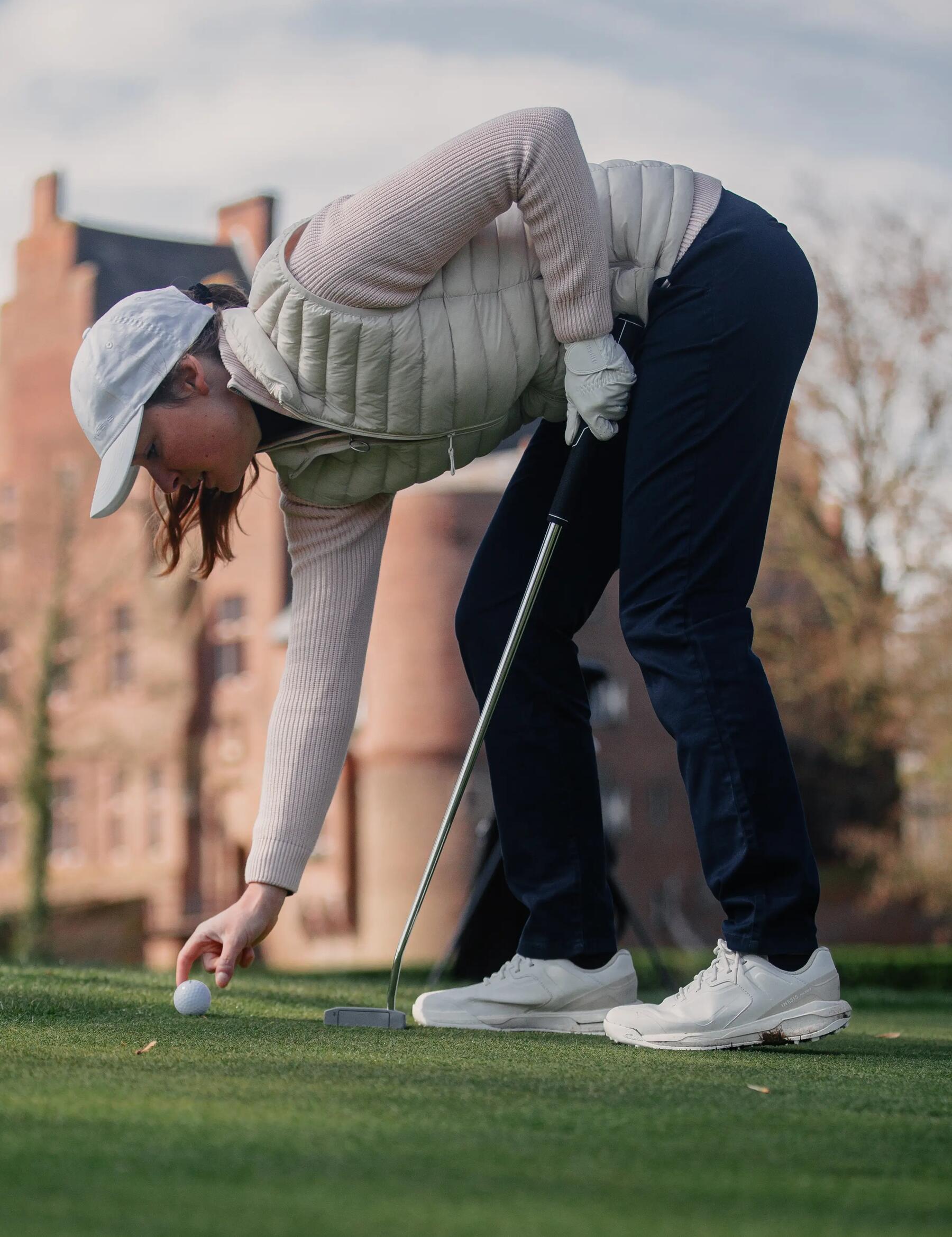 Kobieta w butach golfowych na polu golfowym ustawiająca piłkę