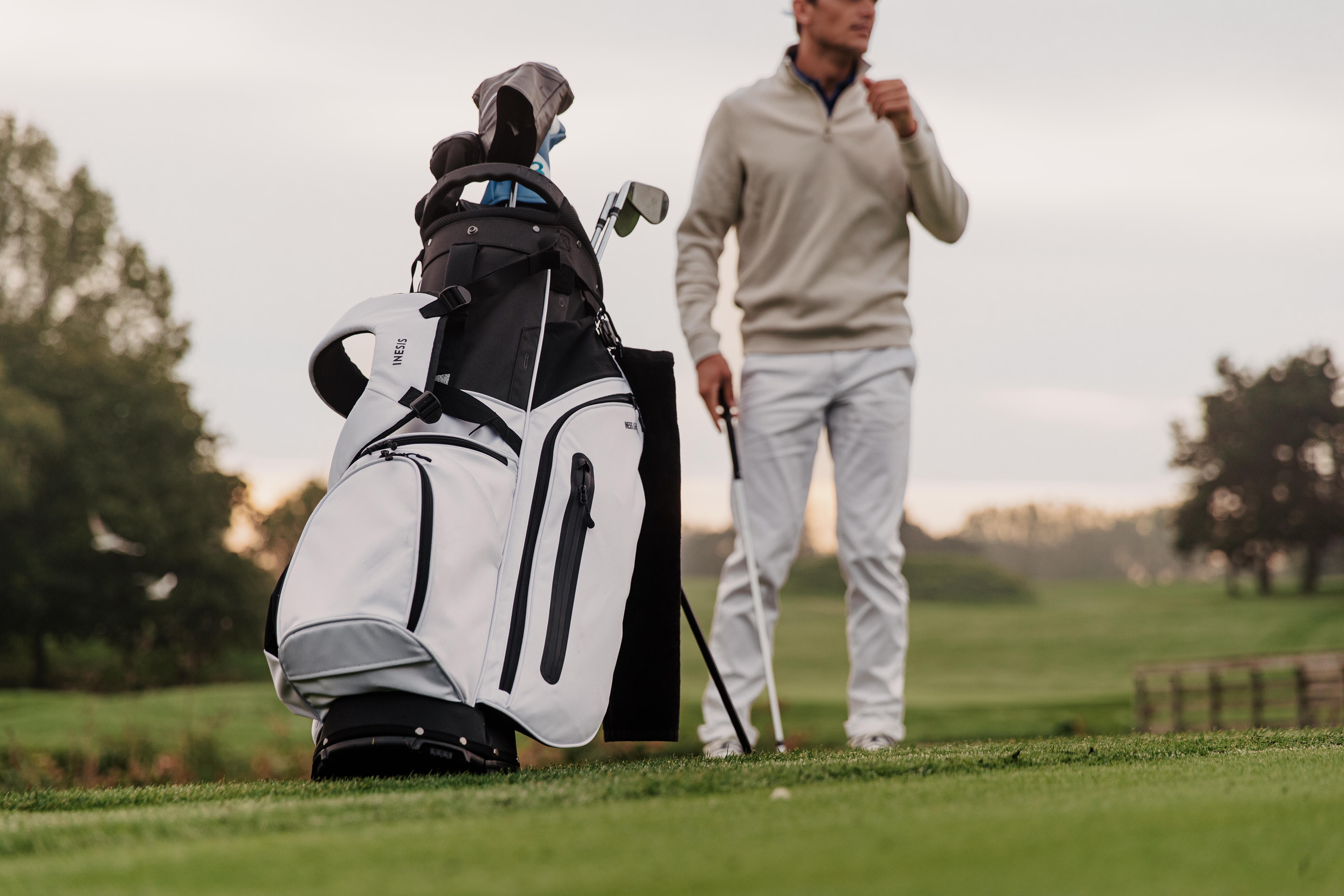 Golf stand bag on course with a golfer holding a club nearby
