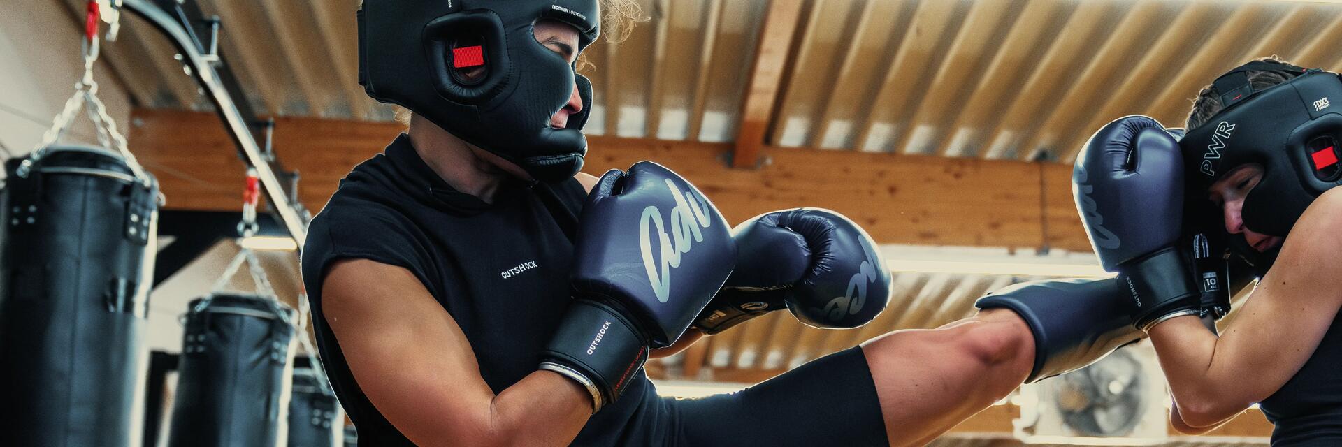 Kobiety w kaskach i w rękawicach trenujące high kick w sztukach walki