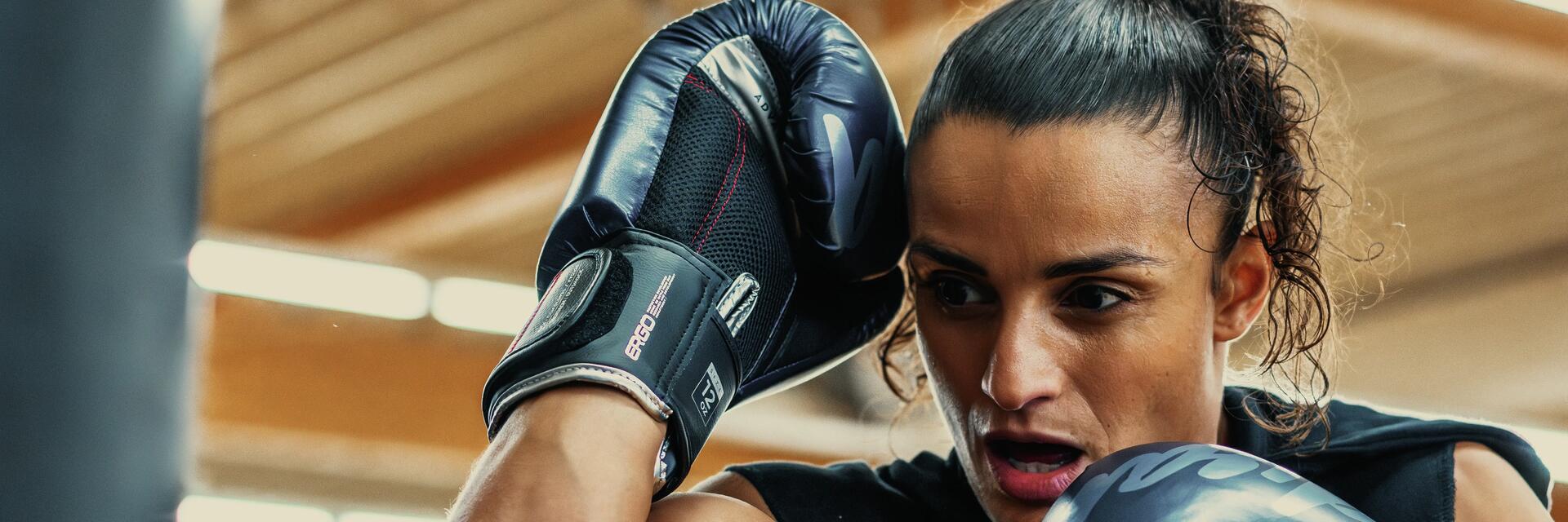 Kobieta w rękawicach bokserskich wykonująca trening mma w domu