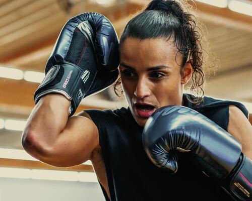 Kobieta w rękawicach bokserskich wykonująca trening mma w domu