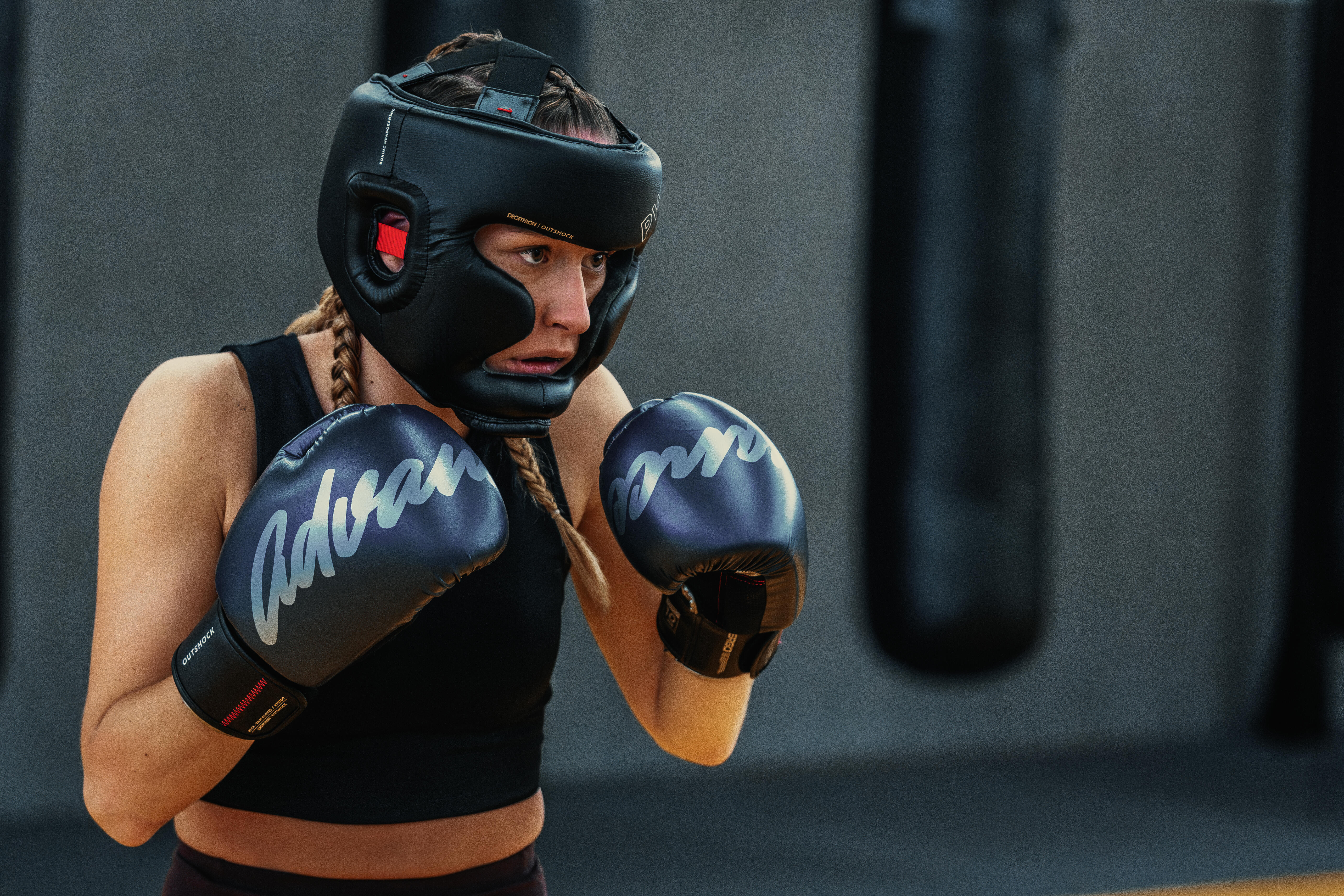 Boxer wearing a black headguard and blue boxing gloves in a guard position