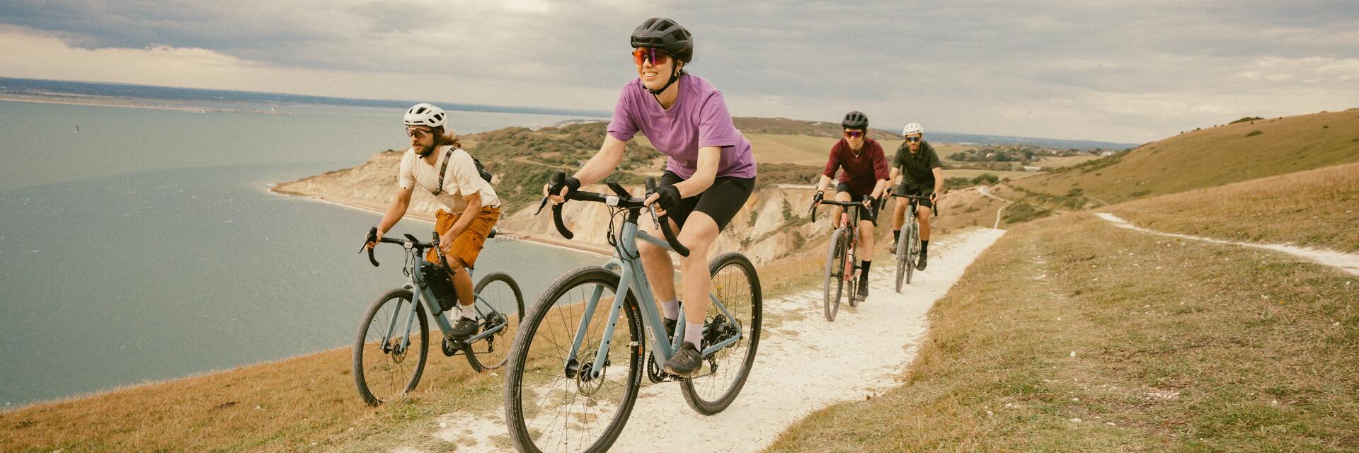 Rowerzyści w kaskach rowerowych jadący na rowerach szlakiem wzdłuż wybrzeża