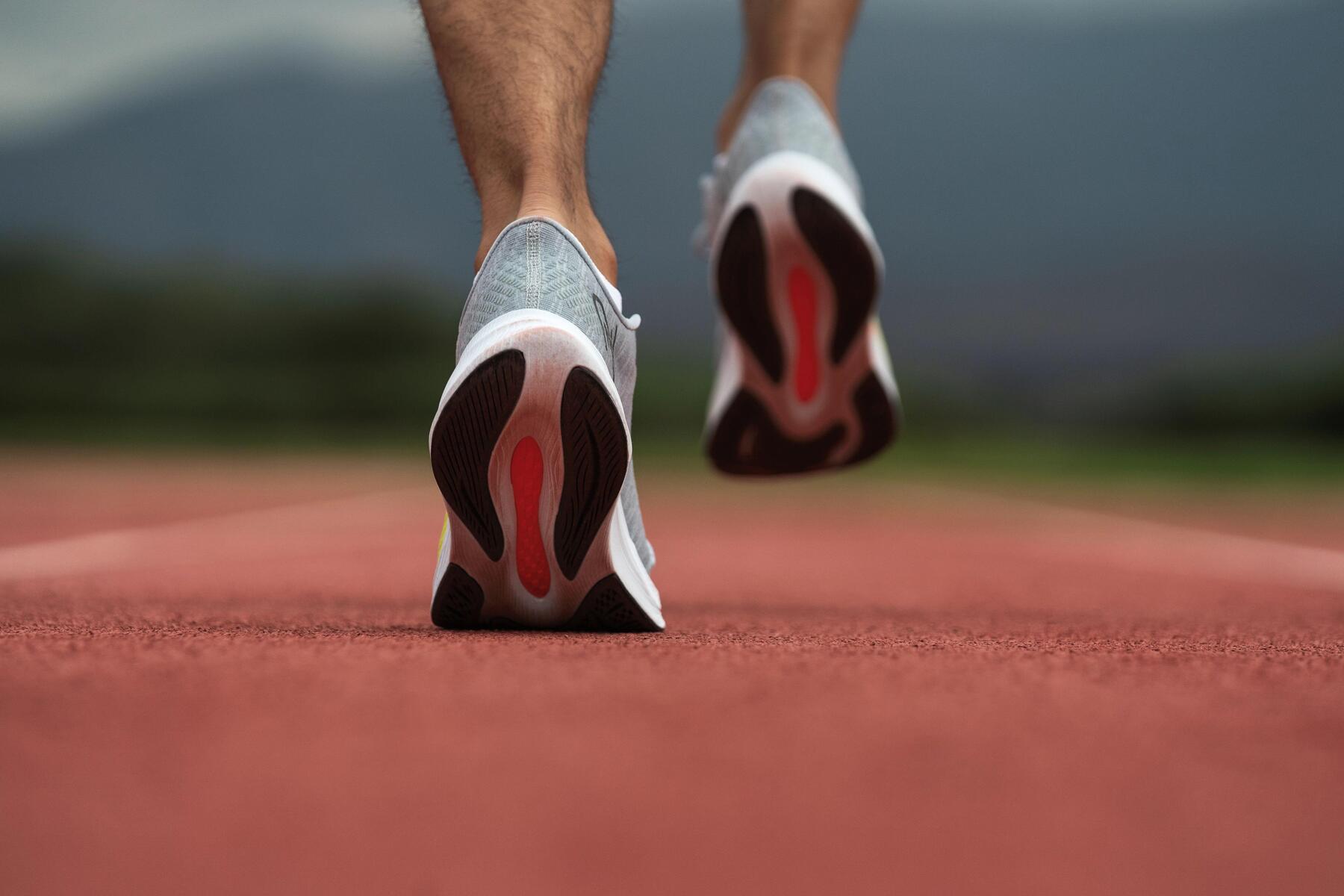 Mężczyzna biegnący tyłem w butach sportowych po bieżni