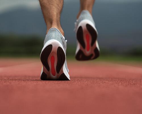 Mężczyzna biegnący tyłem w butach sportowych po bieżni
