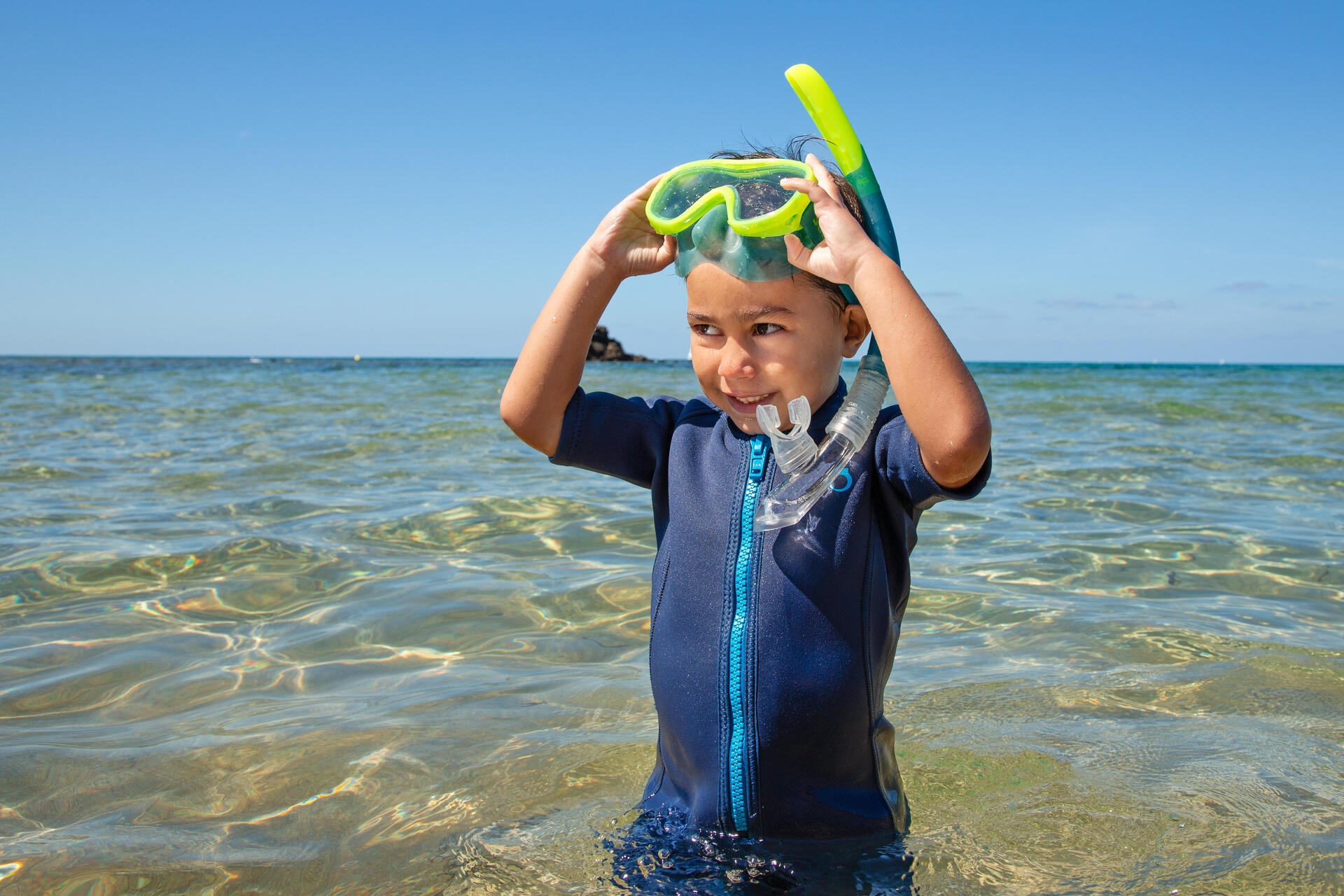 Dziecko stojące na brzegu morza w masce do snorkelingu
