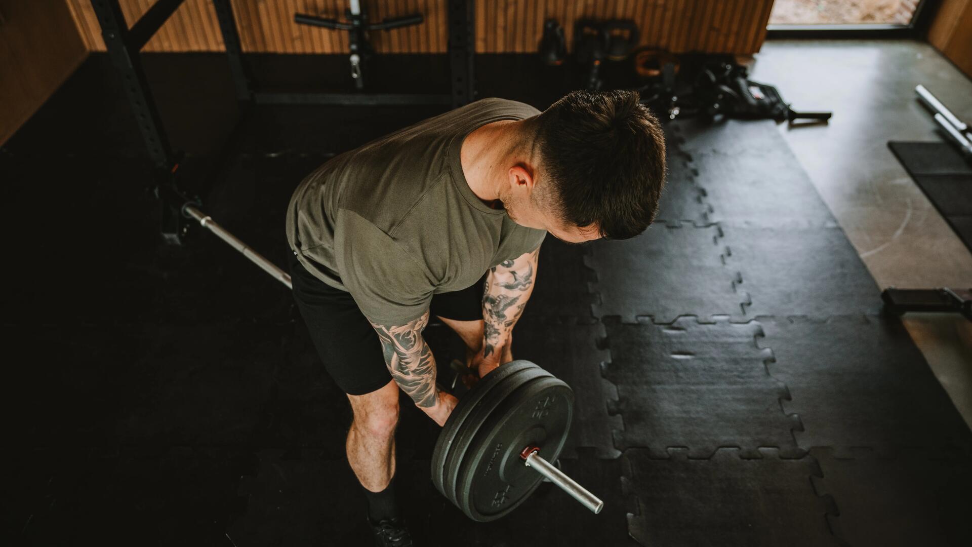 hombre haciendo remo con barra y discos 
