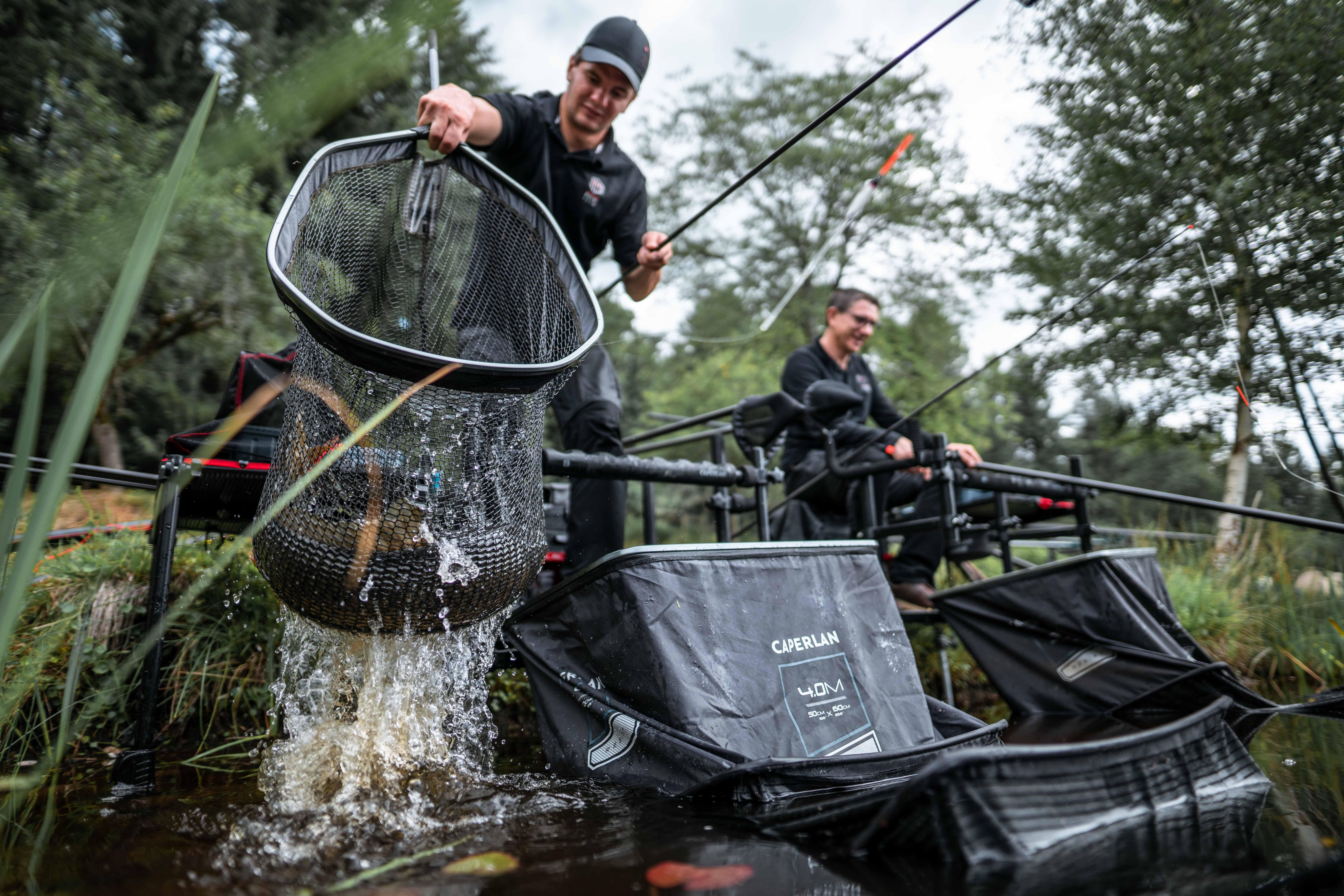 Angler lifting a keepnet from the water after fishing