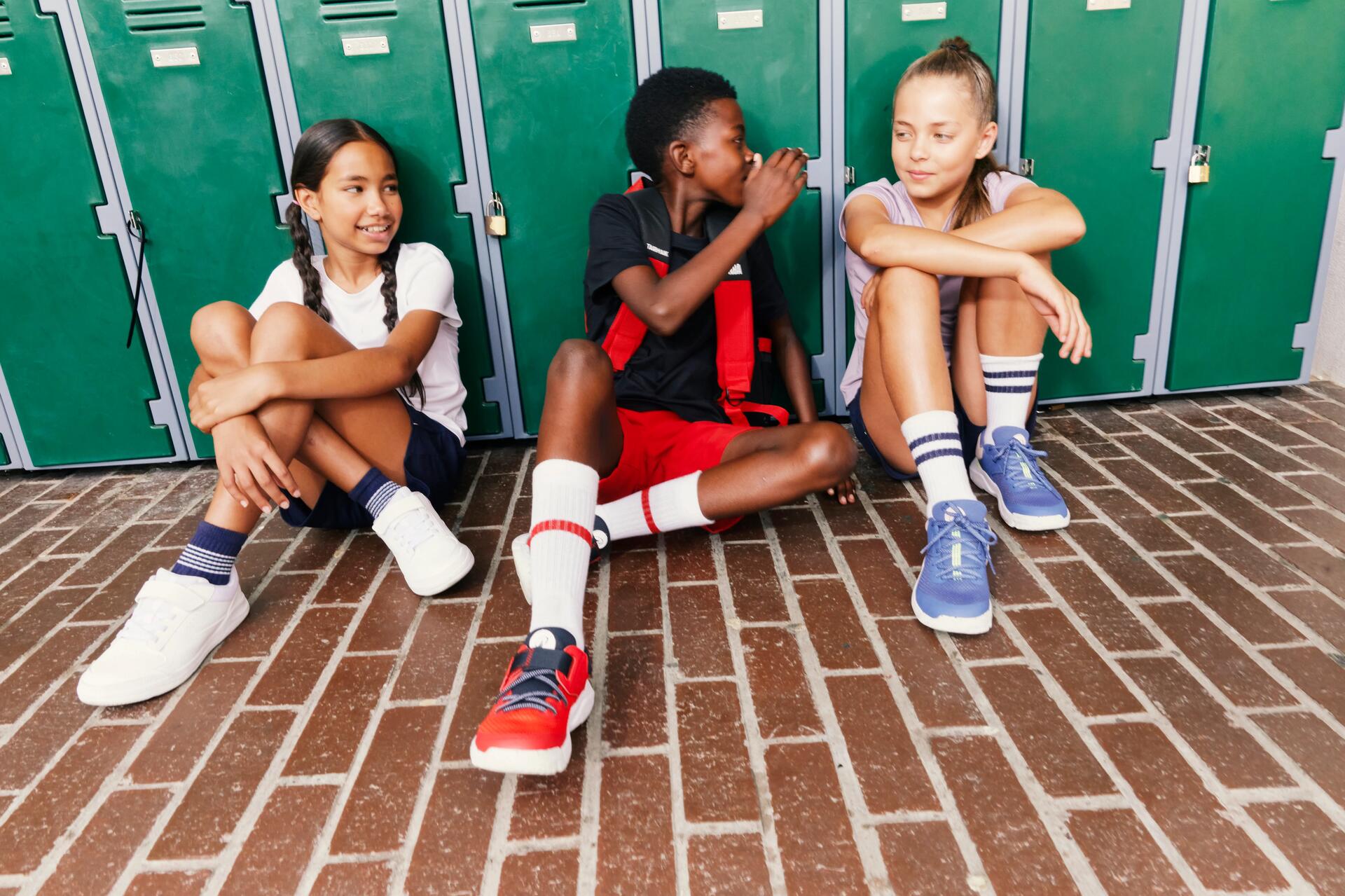 Drie kinderen op school die tegen lockers leunen