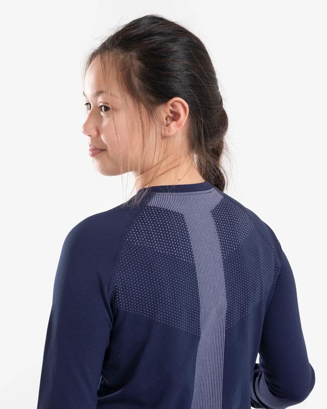 Mädchen in dunkelblauem Shirt mit grauen Mustern, weiße Hintergrundfläche.