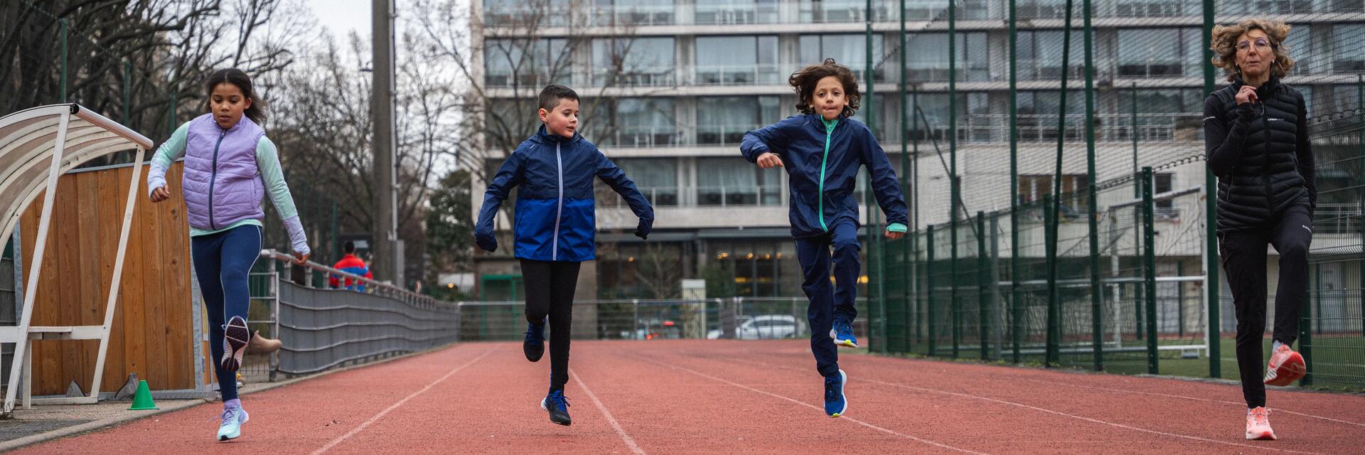 Dzieci biegające z trenerką na treningu lekkoatletycznym
