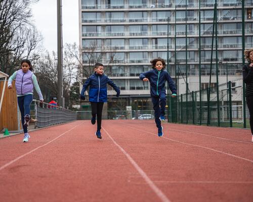 Dzieci biegające z trenerką na treningu lekkoatletycznym