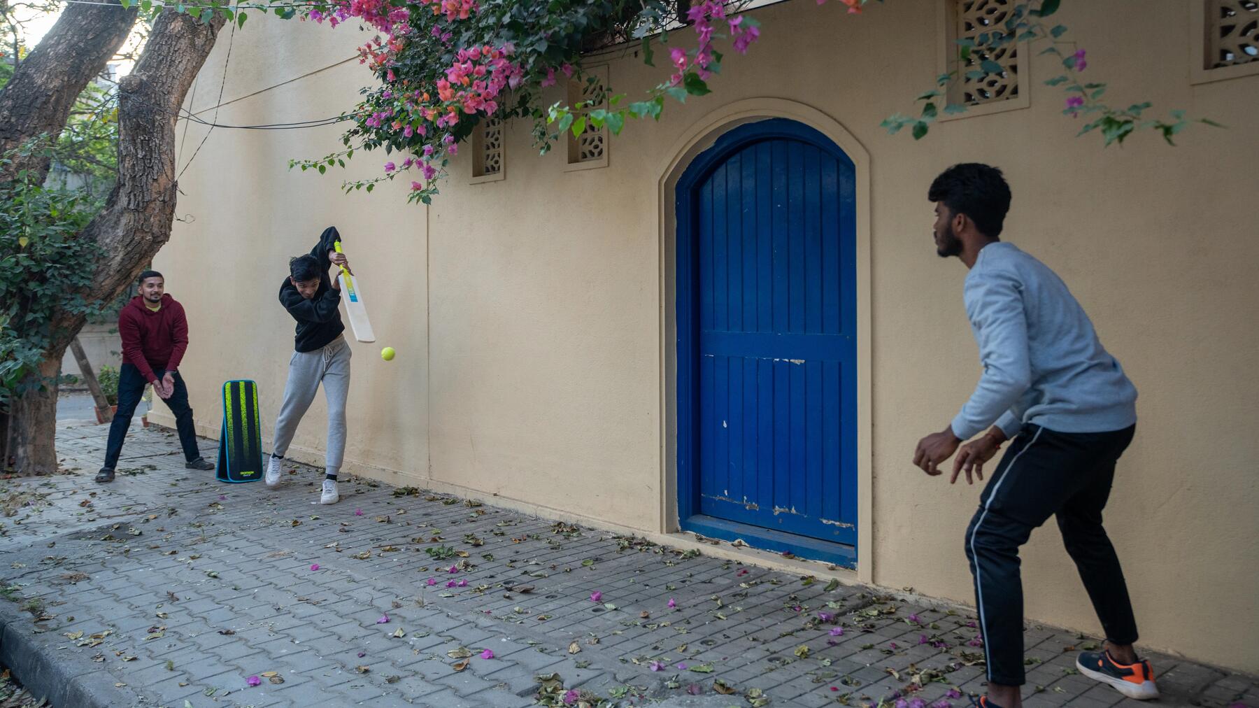 Eine Gruppe von Männern spielt Cricket in einem Wohngebiet