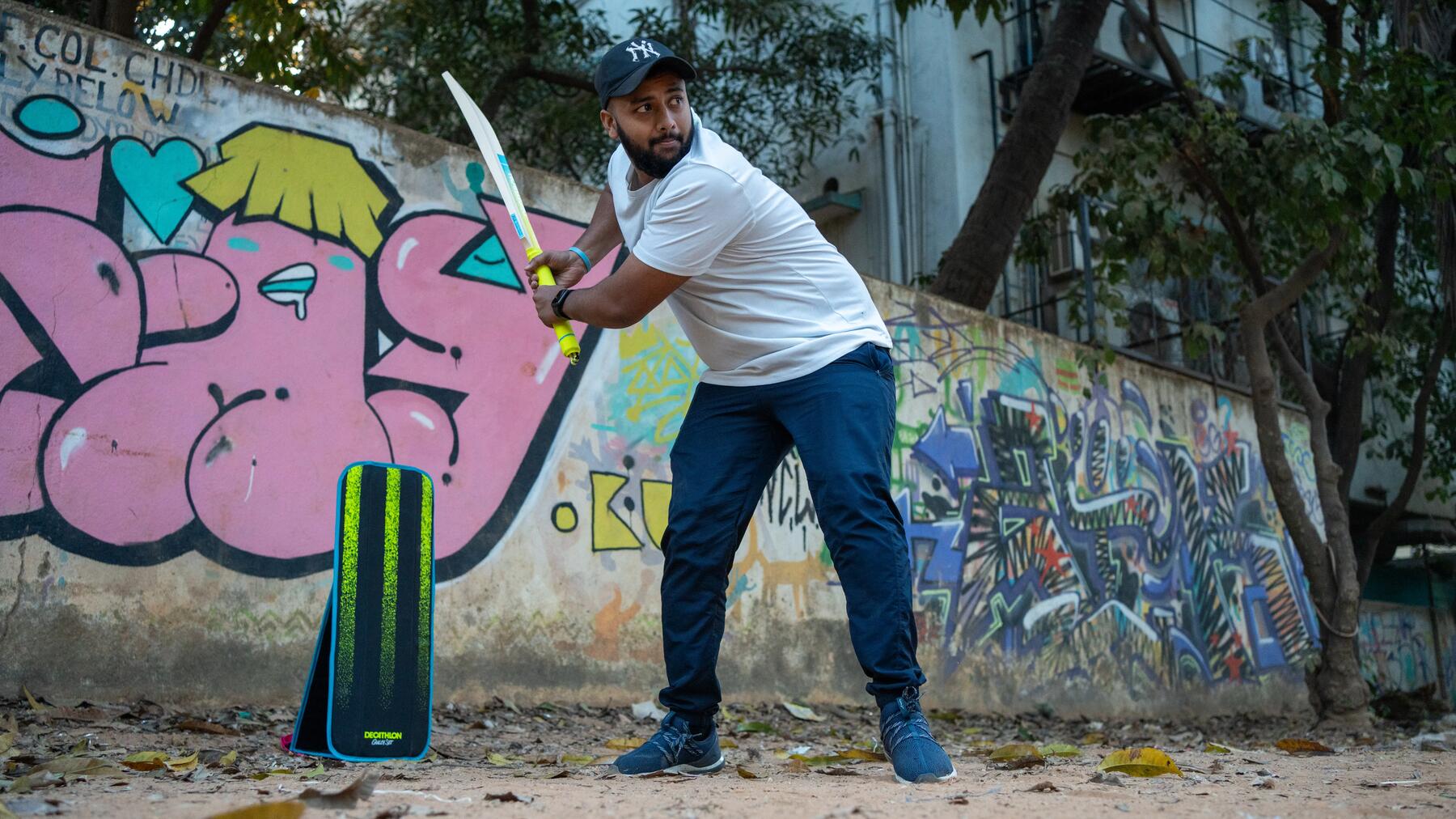 Konzentrierter Mann beim Cricket-Spiel im Freien mit erhobenem Schläger