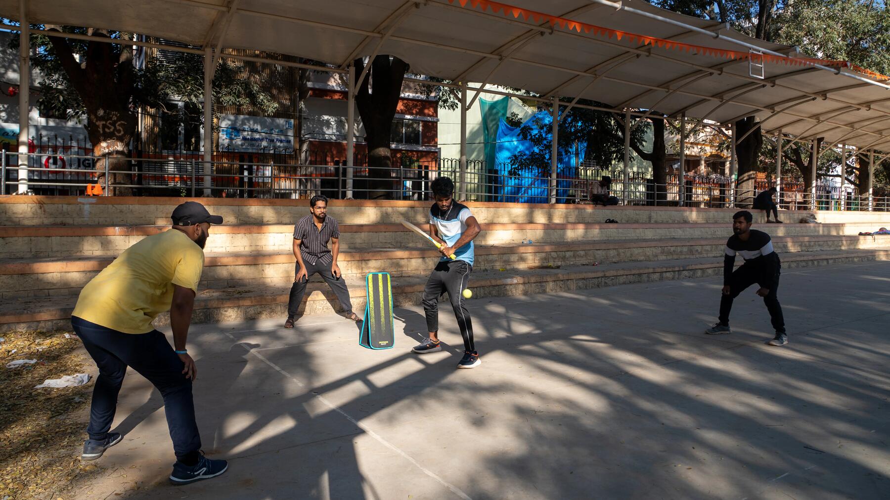 Männer spielen gemeinsam Cricket auf einer Straße im Freien