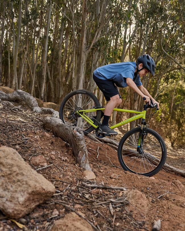 Kind fährt auf gelbem Fahrrad durch den Wald