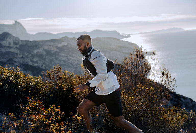Man trail running on a coastal ridge at sunrise