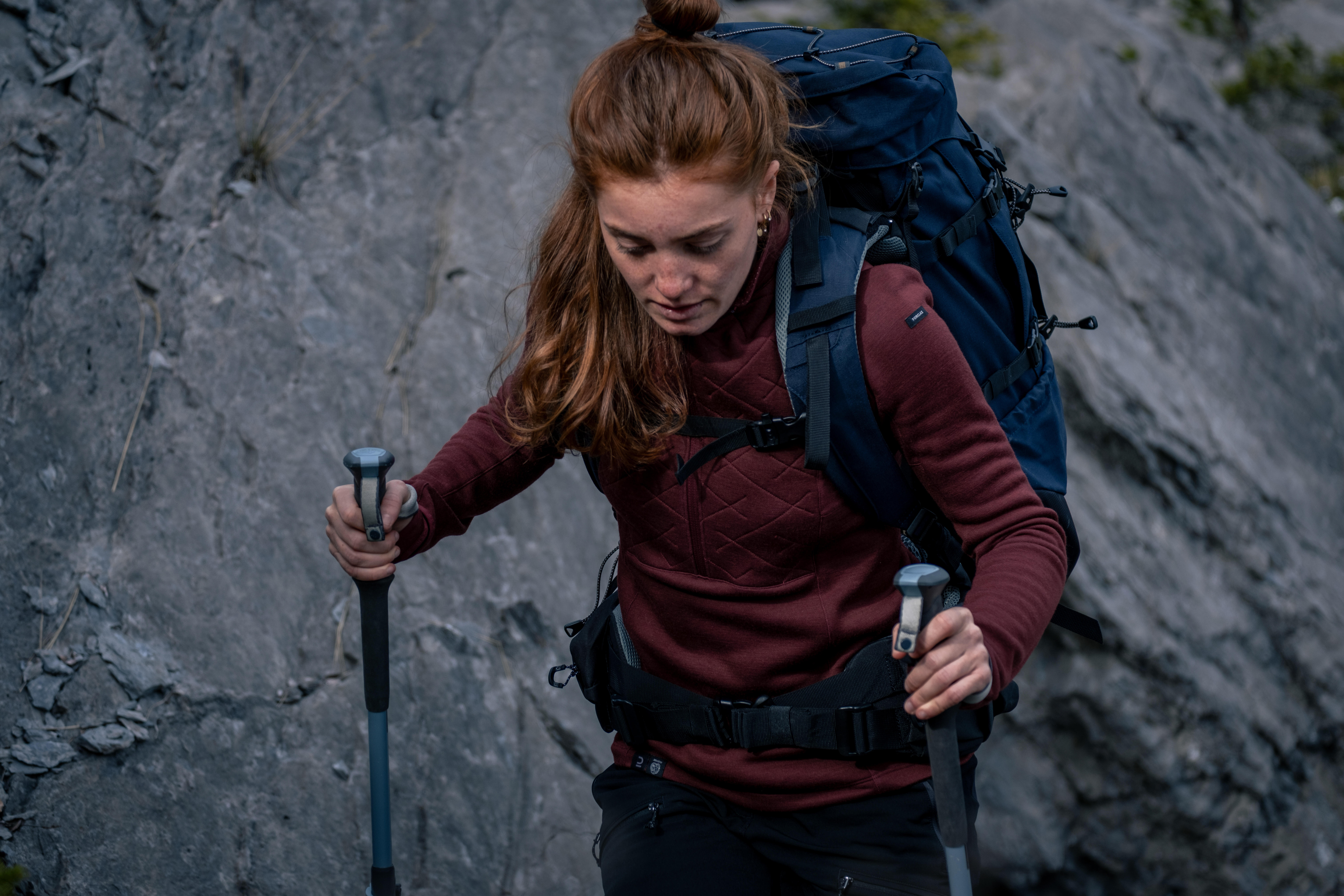 Woman wearing merino wool thermals while hiking with trekking poles and a backpack