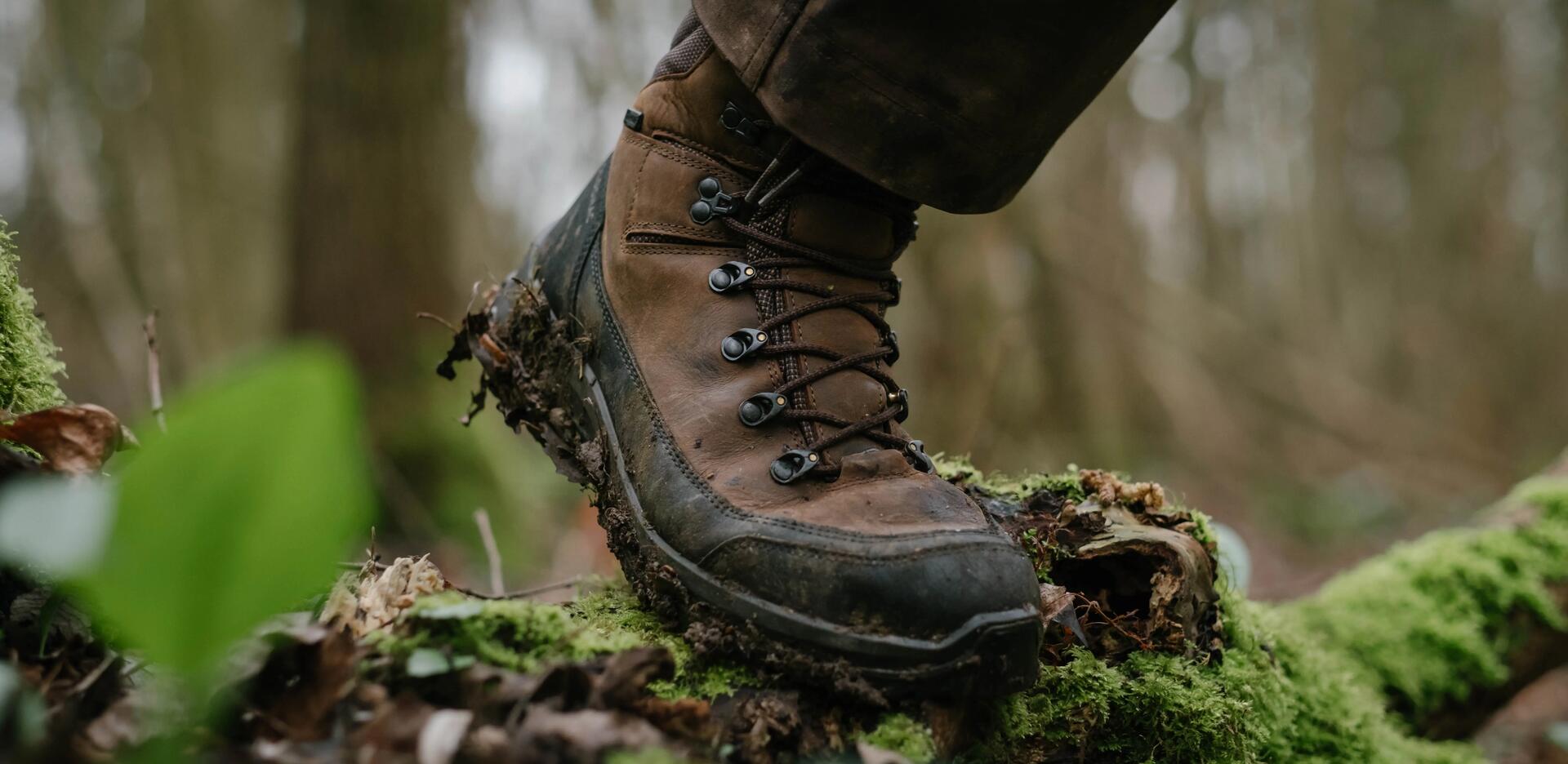 Un chasseur avec une paire de chaussures de chasse aux pieds qui passe sur une branche
