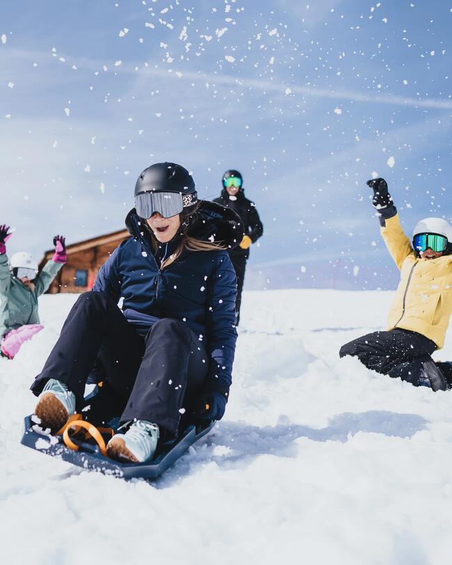 Kinder fahren Schlitten den Berg runter