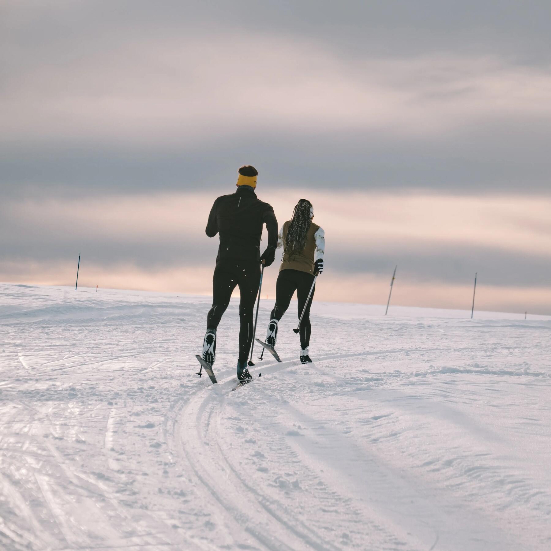 un homme et femme qui pratiquent le ski de fond au couché du soleil