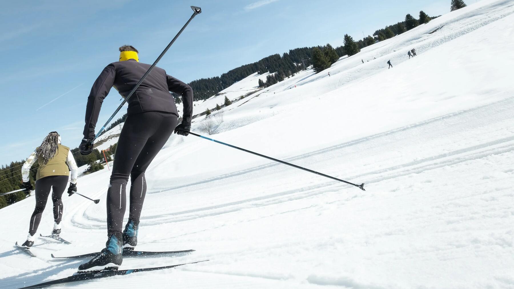 Zwei Langläufer im Skating Stil unterwegs im Schnee in Langlaufbekleidung.