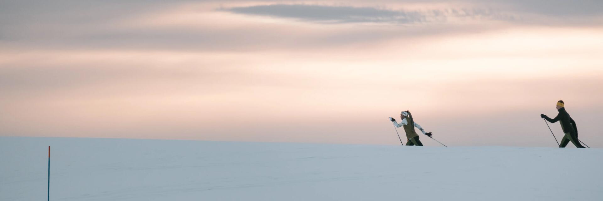 Zwei Langlaufläufer in der verschneiten Natur  mit Langlaufbekleidung unterwegs.