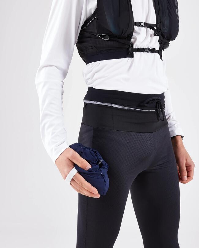 Läufer in schwarz-weißer Sportkleidung hält dunkle eingepackte Jacke in der Hand.