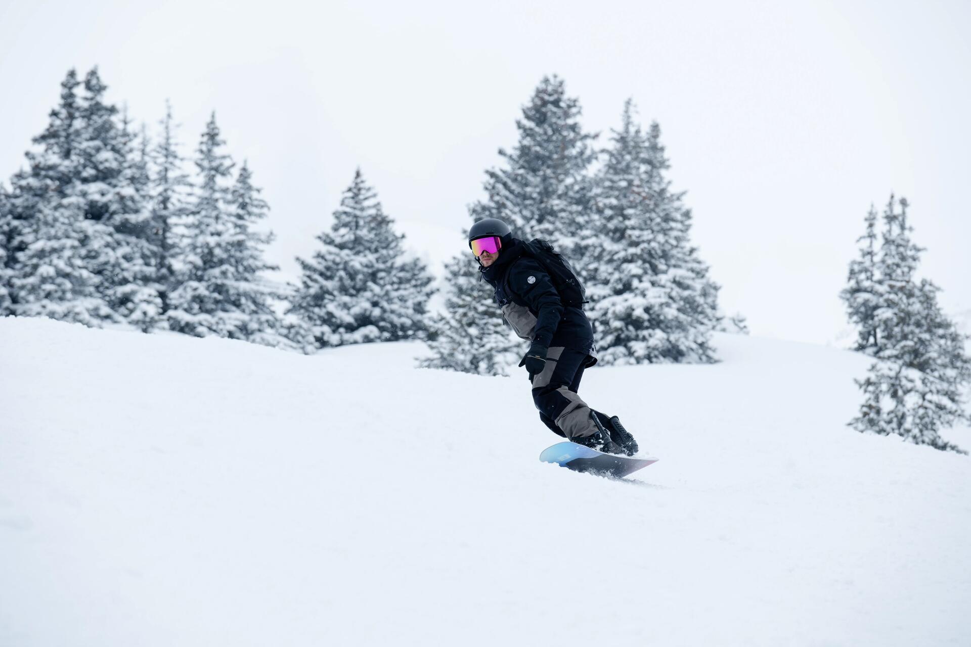 Mężczyzna w kasku i w goglach jeżdżący na snowboardzie