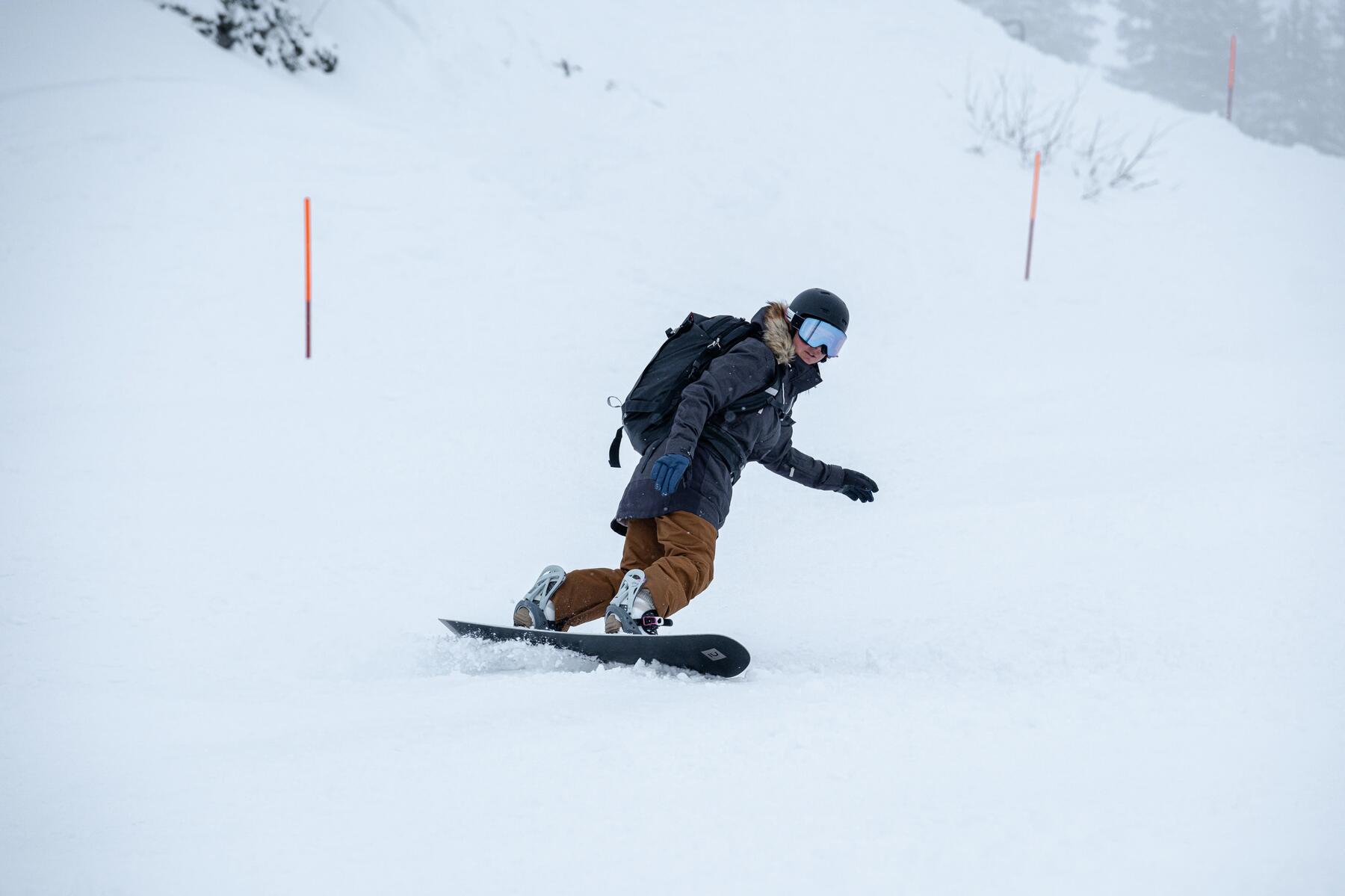 Mężczyzna uprawiający snowboard w kasku goglach i rekawicach wielopalcowych