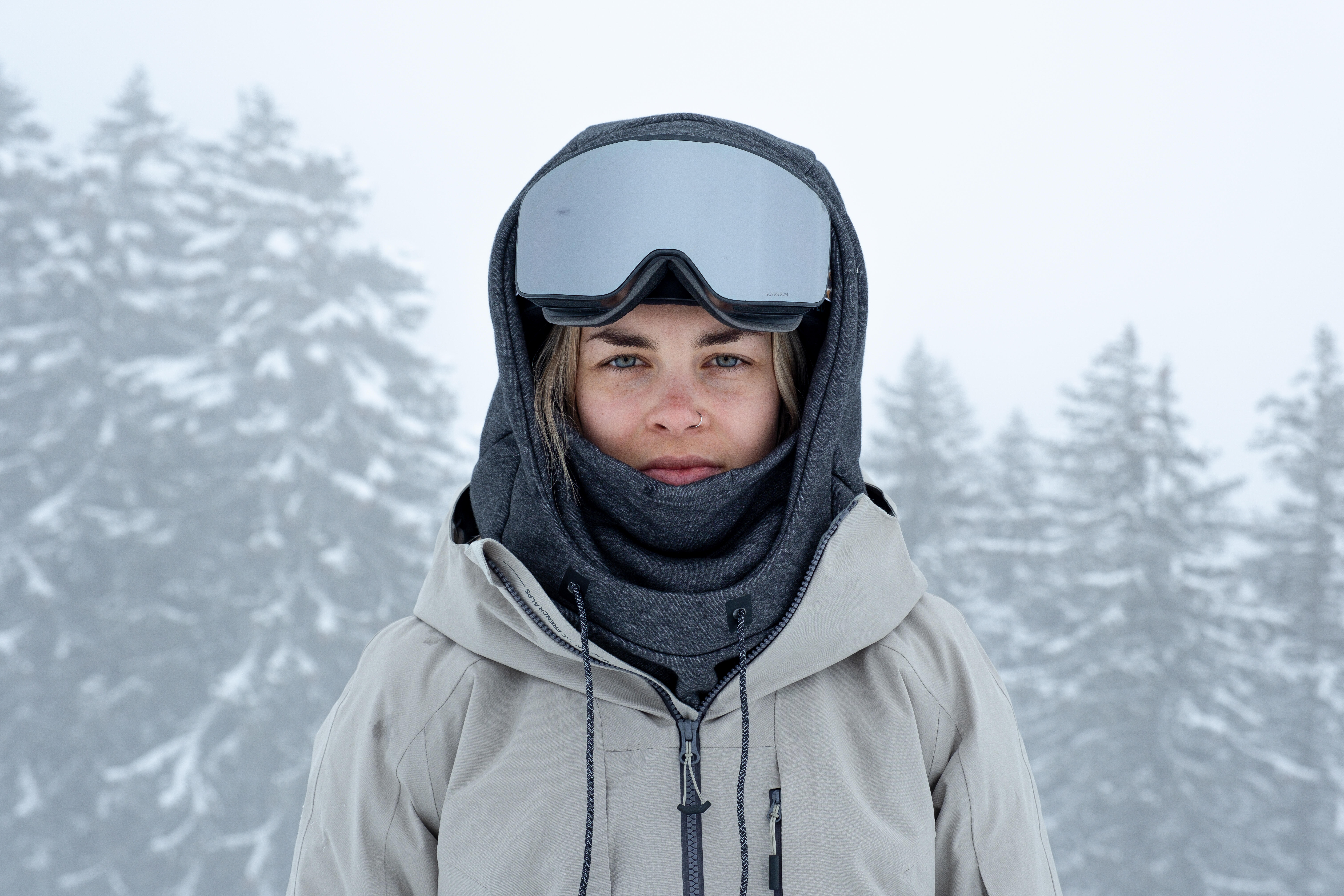 Woman wearing a grey balaclava and ski goggles in snowy conditions