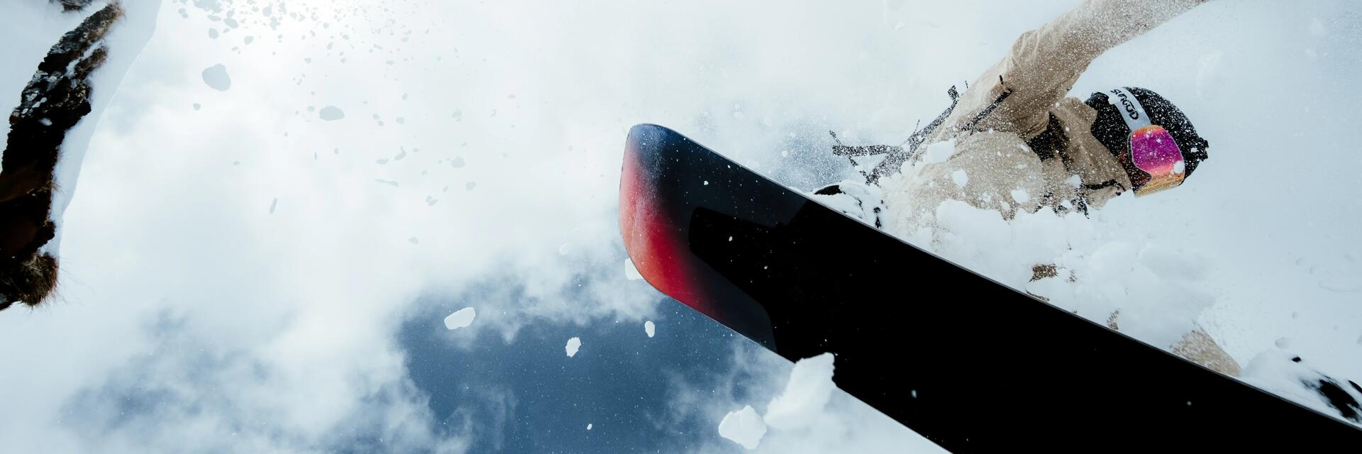 Osoba w kasku i w goglach jadąca na snowboardzie