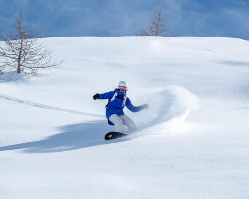 Kobieta w kasku i w goglach jeżdżąca na snowboardzie