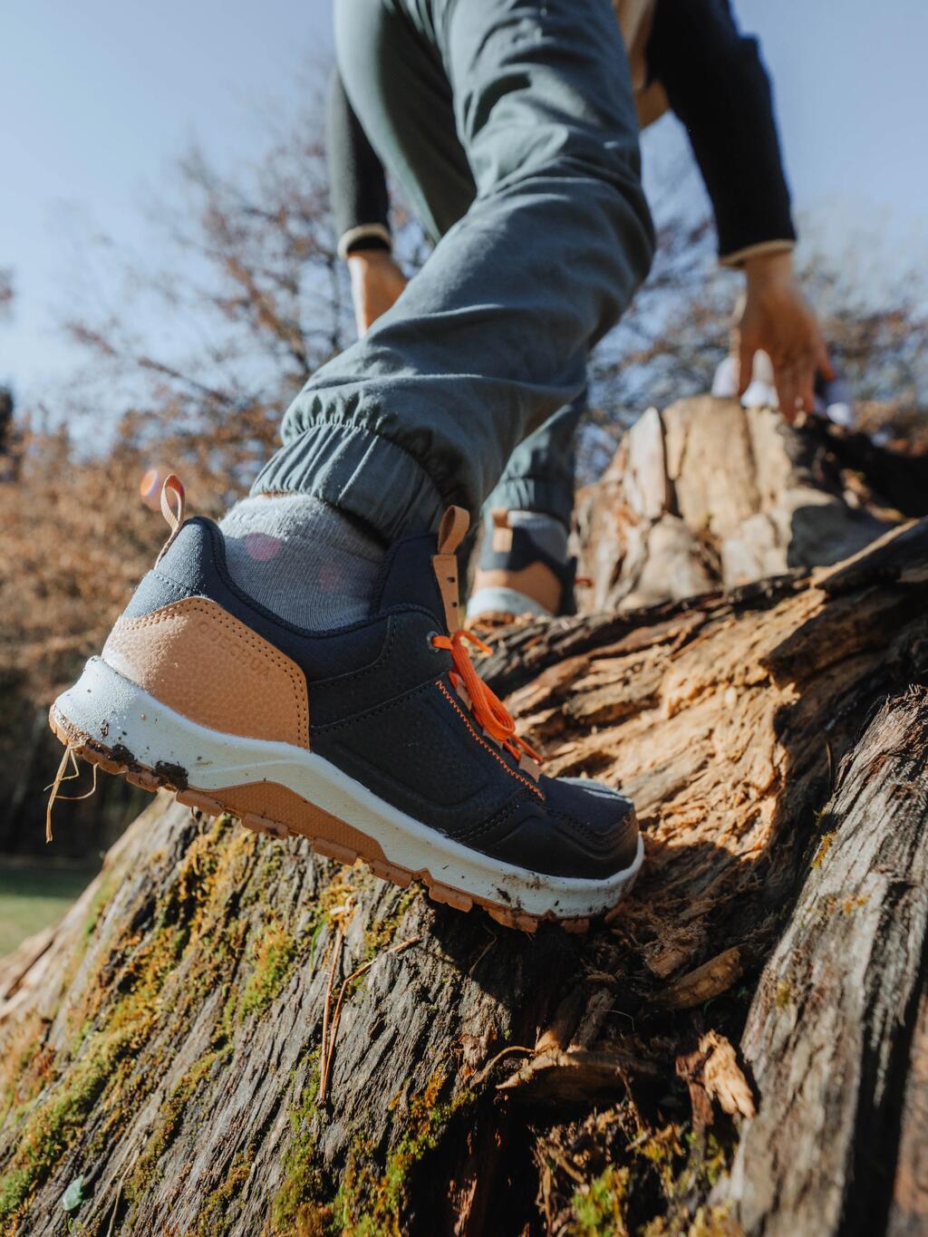 Deček z modrimi in oker čevlji pleza po drevesu.