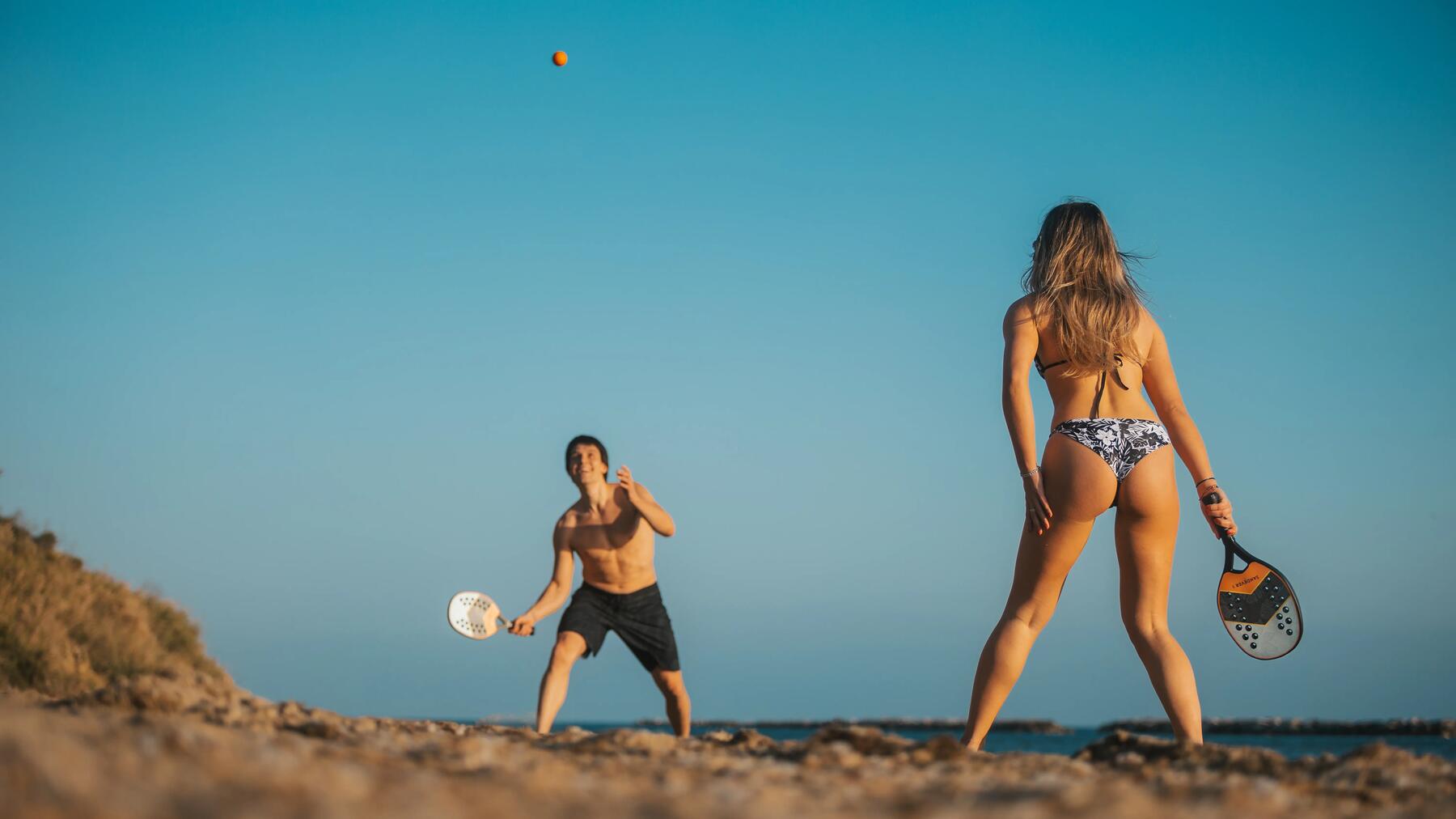 Kobieta grająca w padla na plaży w stroju kąpielowym