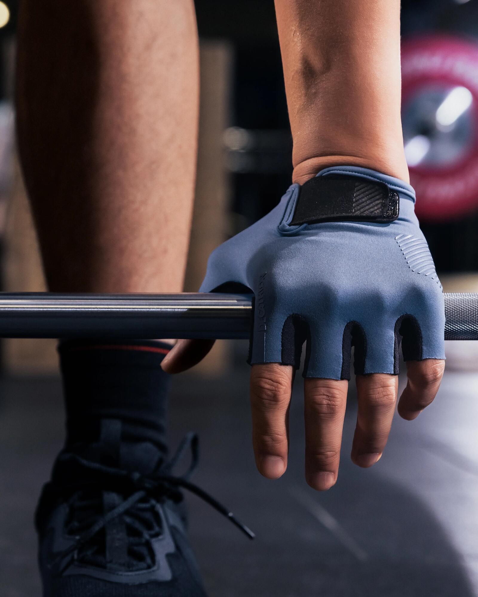 Hand mit blauem Fitnesshandschuh greift im Fitnessstudio nach einer Langhantel.