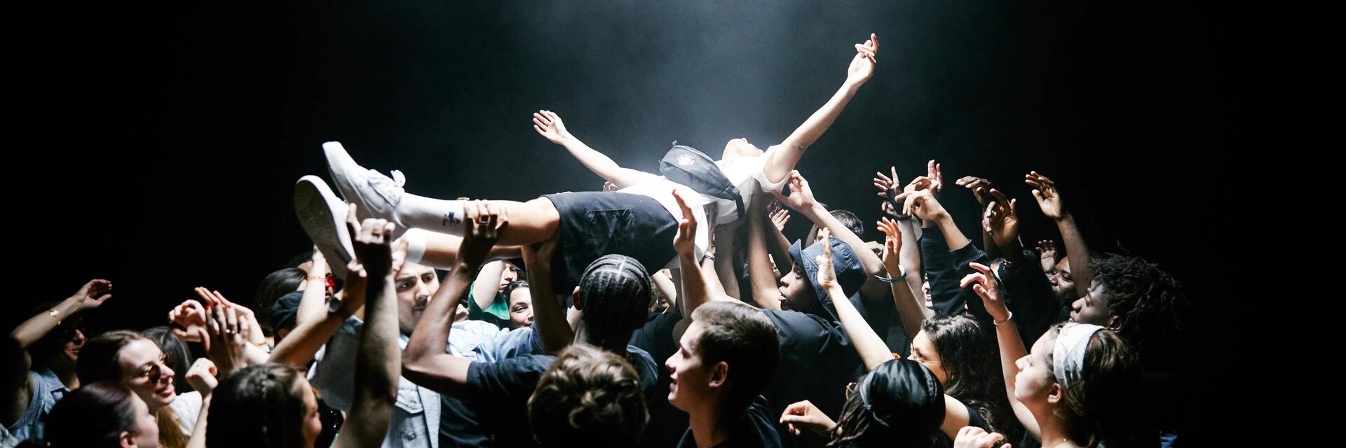 Menschentraube beim Stagediving auf einem Festival bei Dunkelheit
