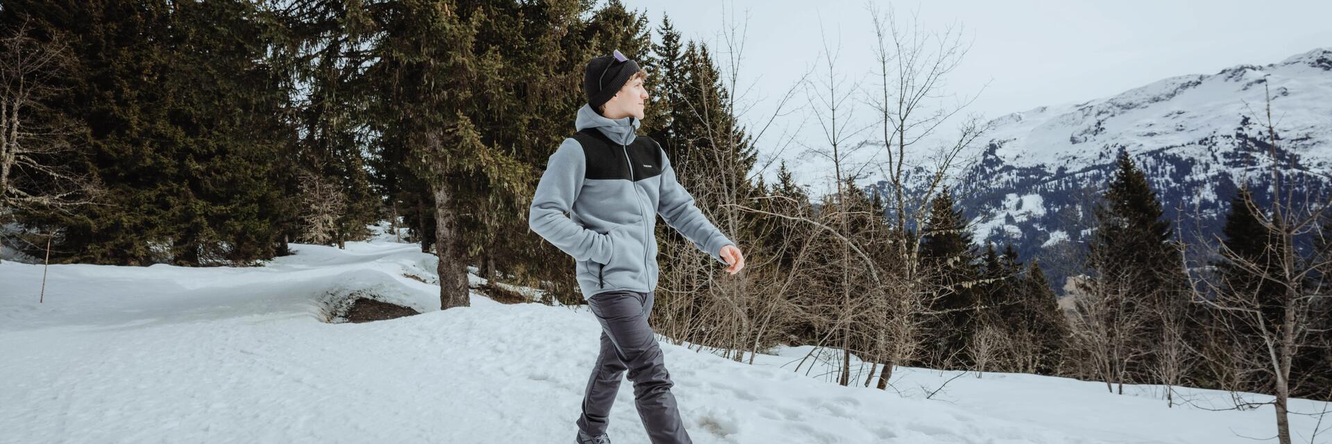 Mężczyzna idący po śniegu podziwiający Tatry polskie