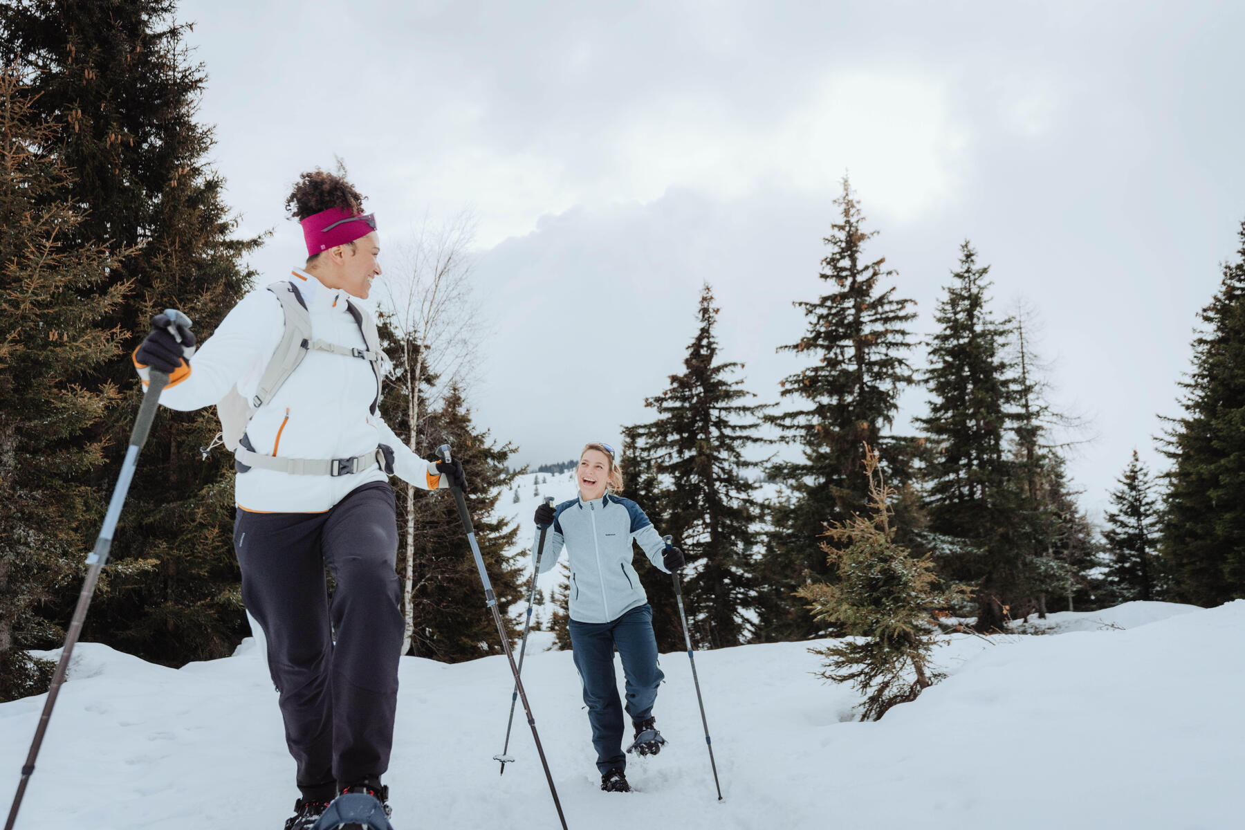 Zwei Personen im tiefsten Winter haben Spaß am Winterwandern. Sie haben beide Skistöcker zum halt dabei