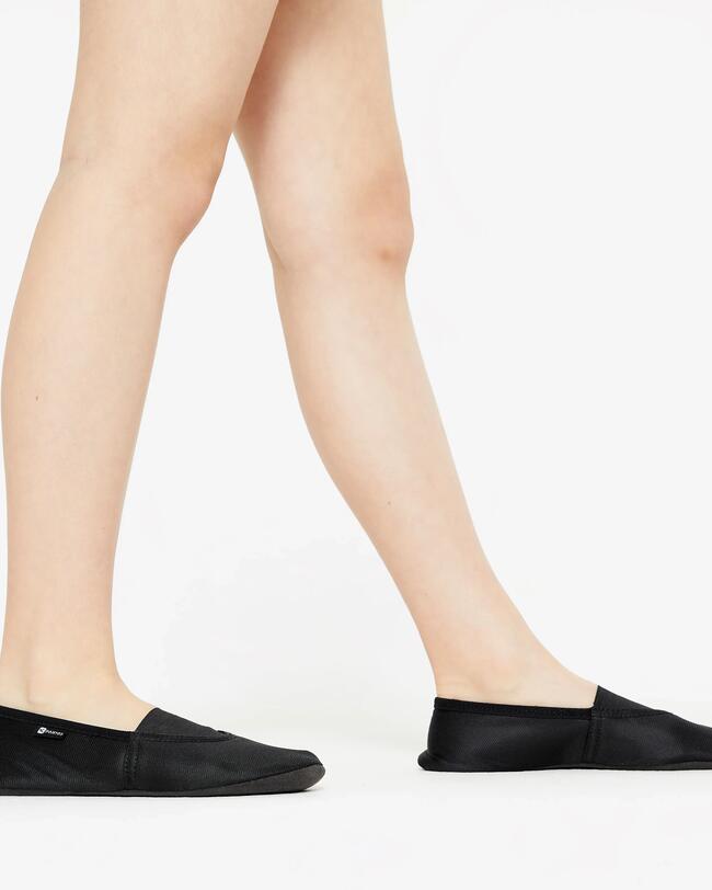 Eine Frau trägt schwarze Gymnastikschuhe.