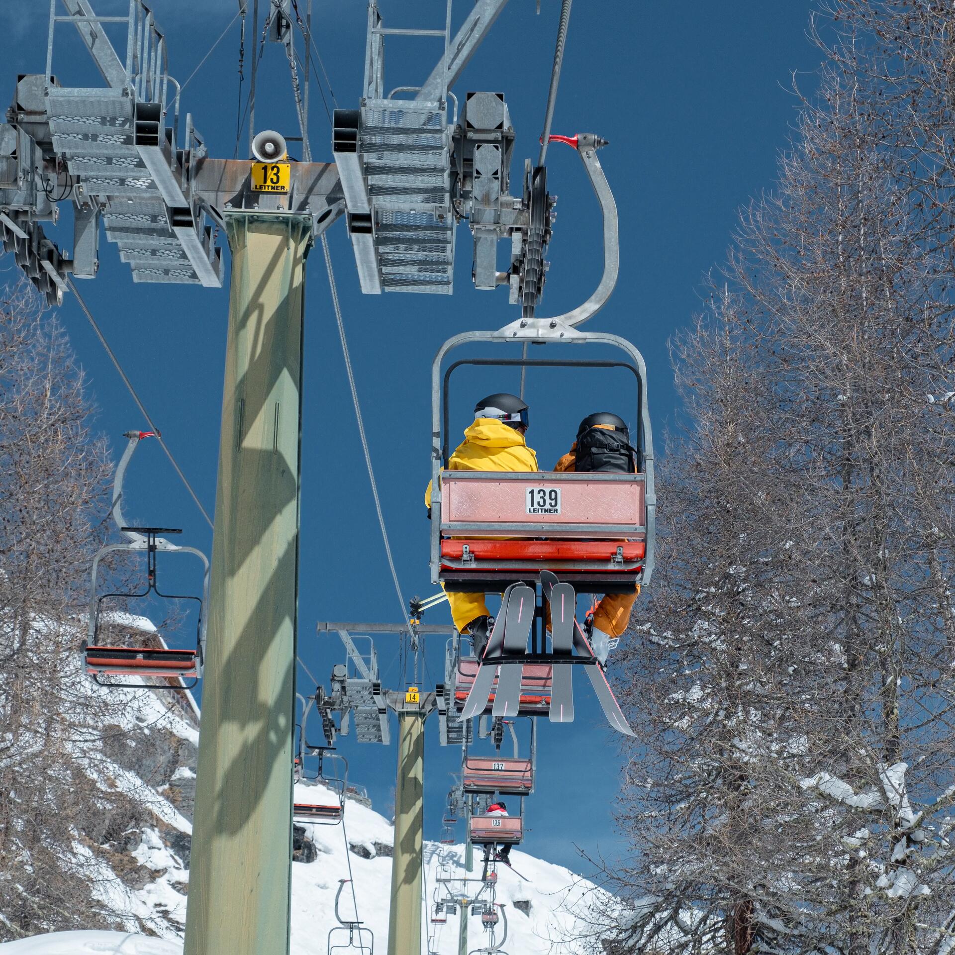 Skilift mit zwei Menschen in einem Abteil.
