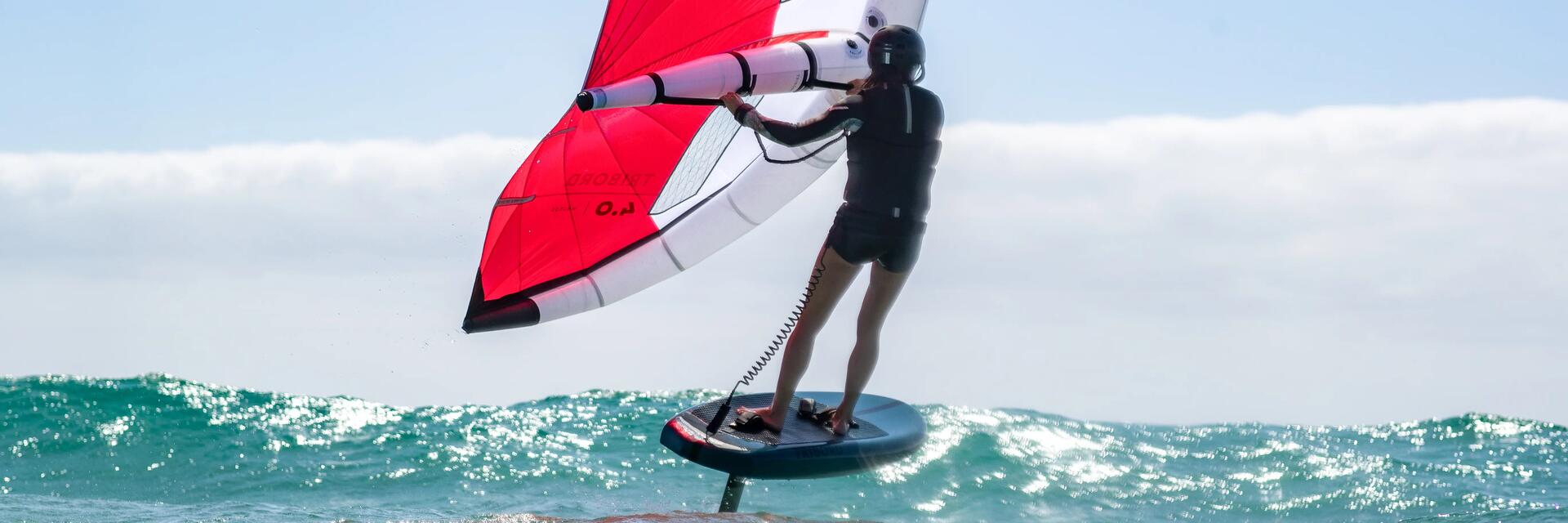 Kobieta w odzieży do uprawiania sportów wodnych pływająca na desce wing foil
