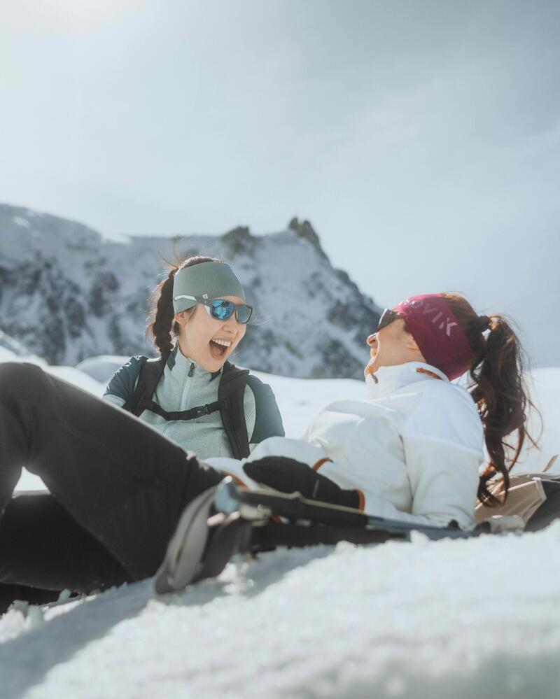Zwei Frauen liegen im Schnee vor Bergen