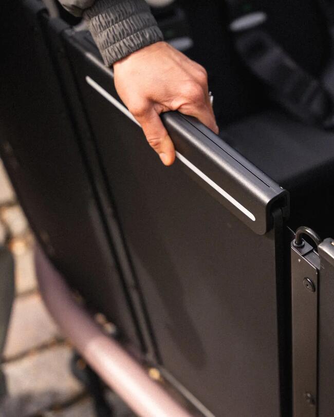 Schwarze Tür der Cargobox, deren Sicherungsmechanismus von einer Hand bedient wird